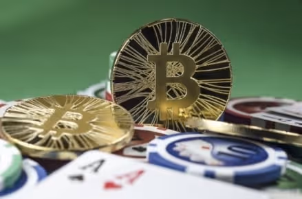 Gold Bitcoin coins with casino chips and playing cards