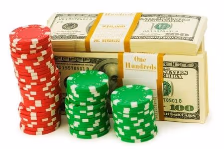 Stacks of red and green casino chips next to bundles of US hundred dollar bills