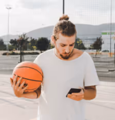 young man holiding basketball and mobile phone